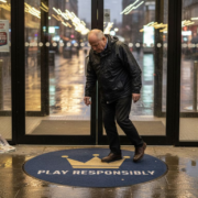 Man entering city casino with play responsibly sign