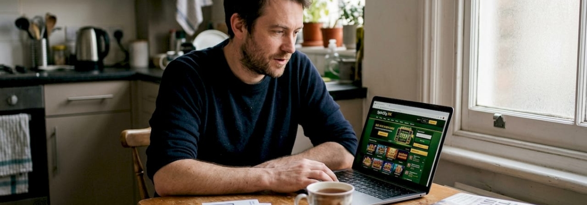 Man browsing online casino site at kitchen table