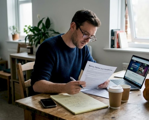 Man reading casino bonus terms at kitchen table