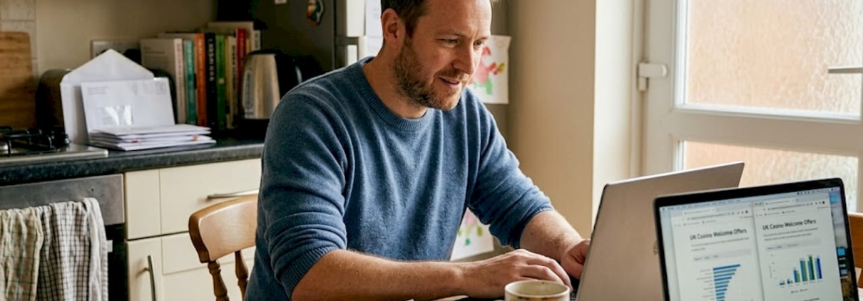 Man comparing casino offers on kitchen laptop
